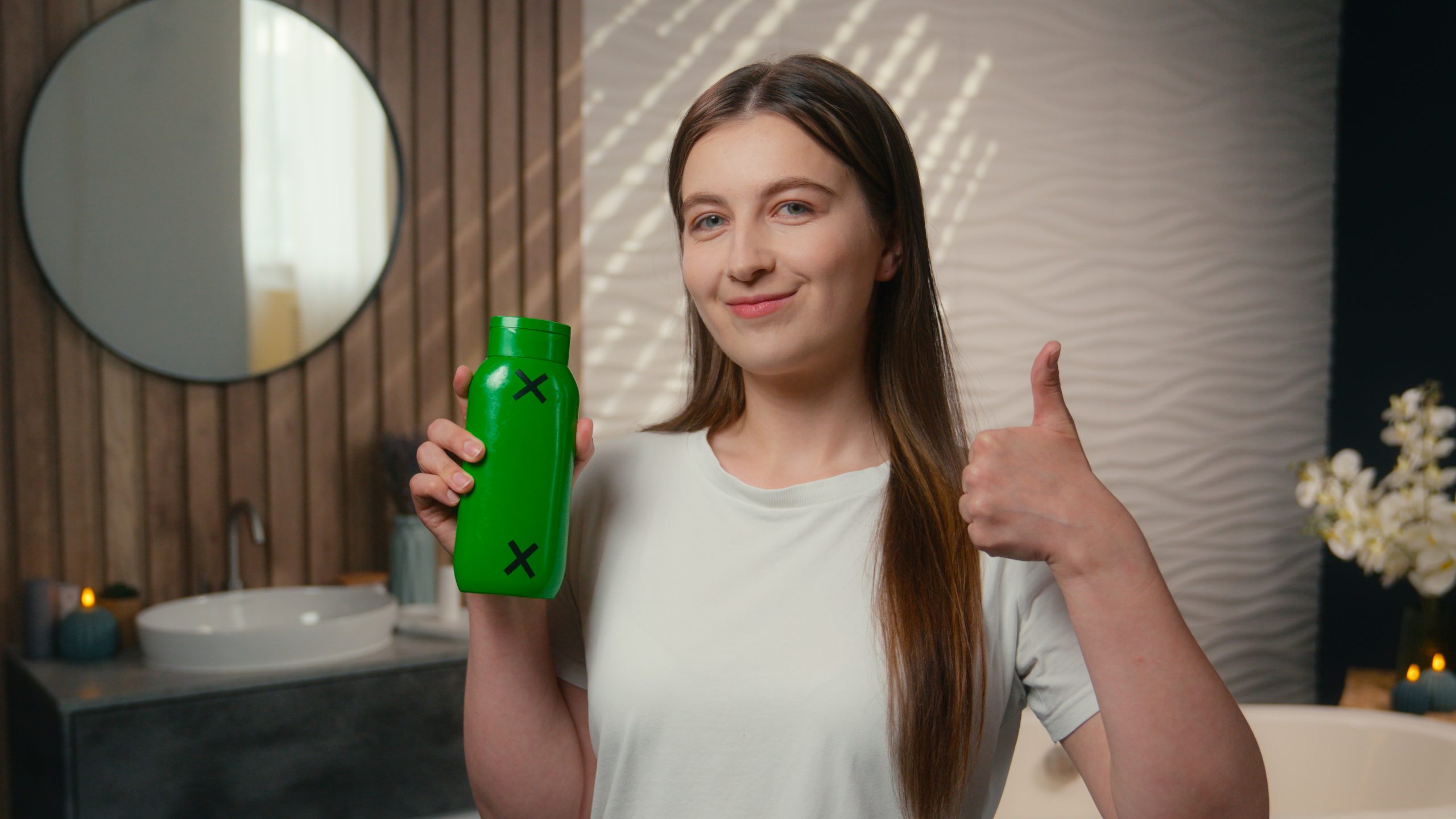 A model massaging shampoo into her scalp in the shower.