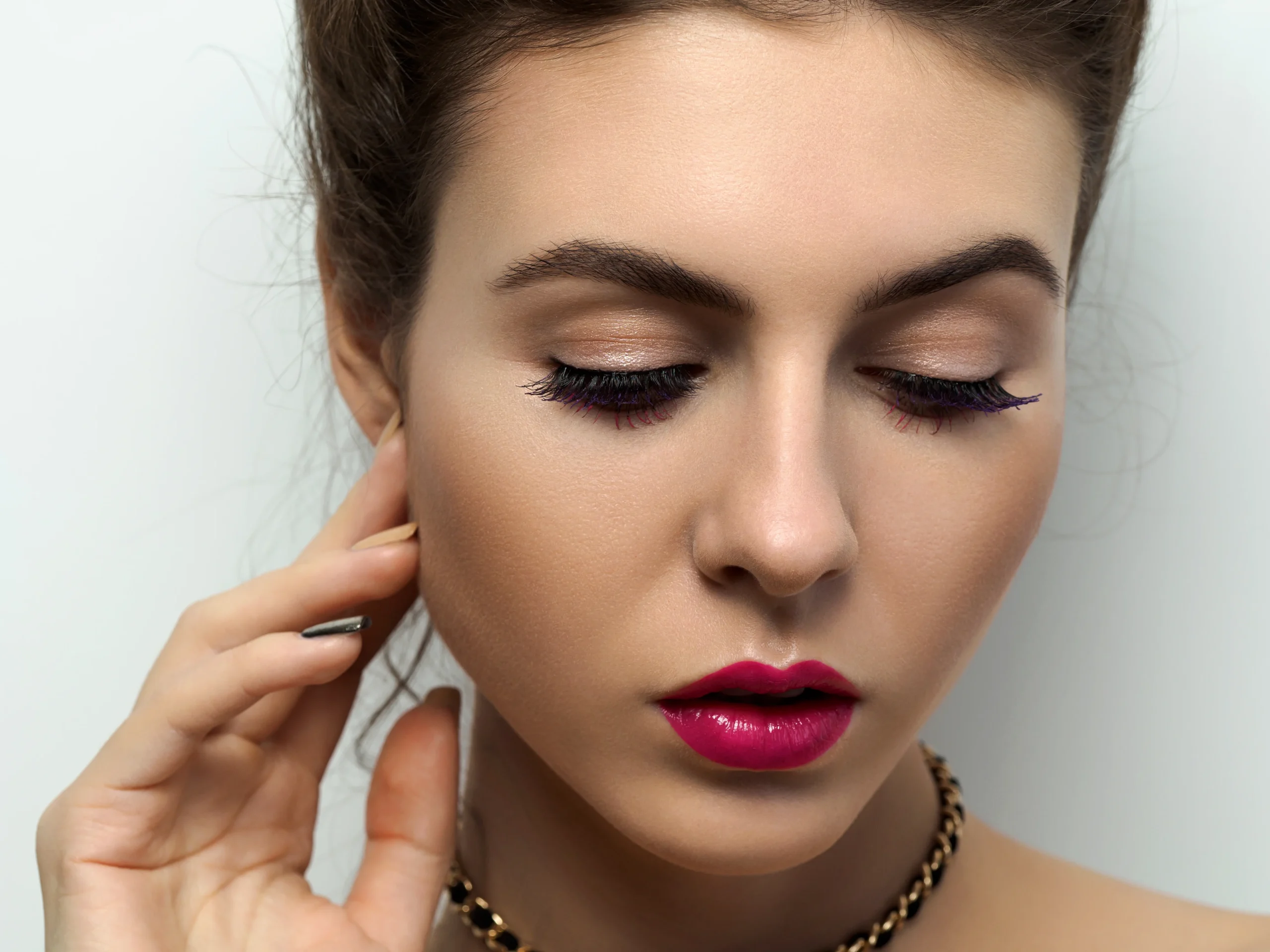 Makeup artist applying eyeshadow before adding eyelash for a flawless finish.