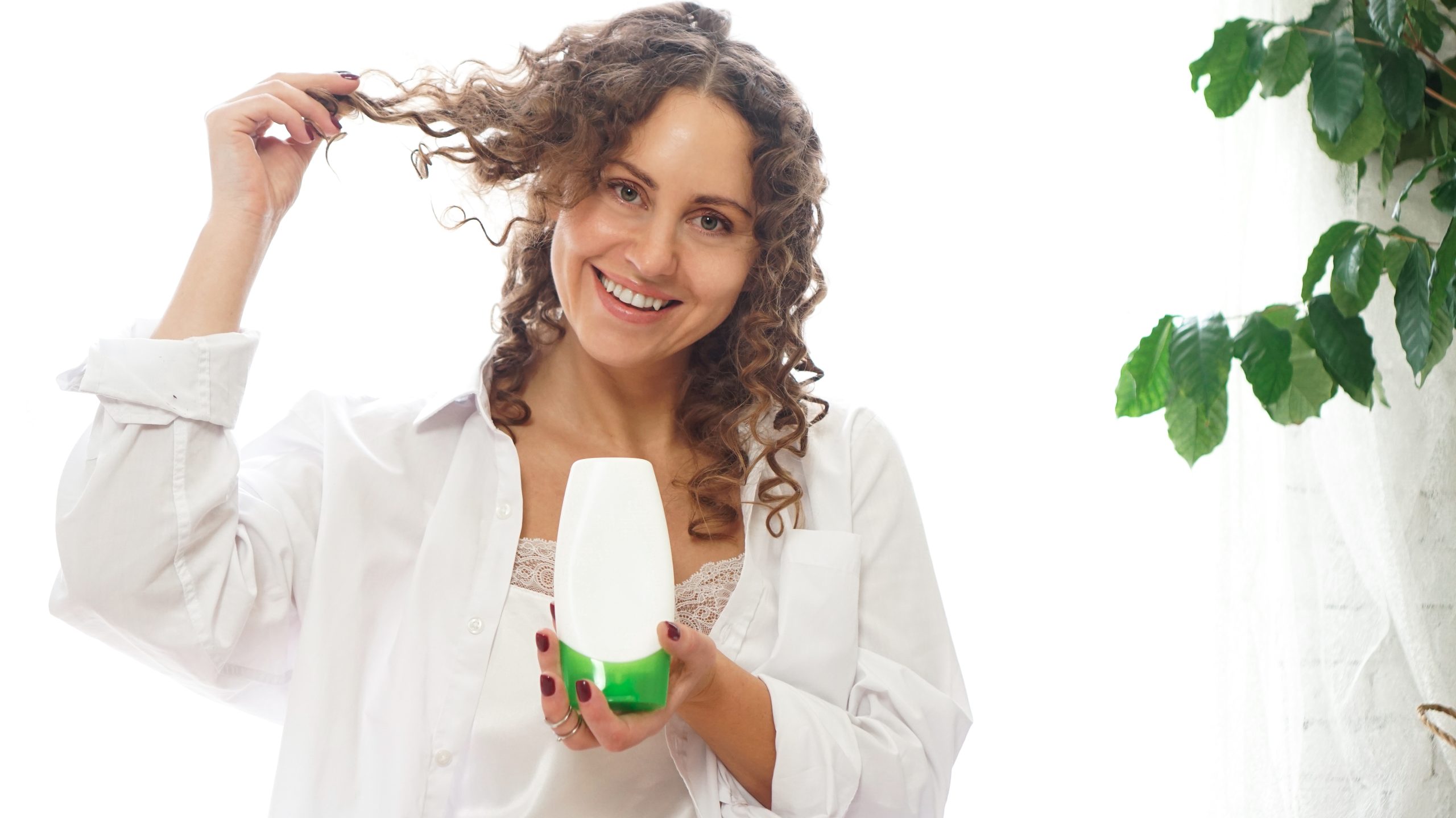 Hands applying deep conditioner to curly hair.