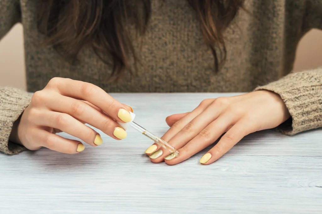 Close-up of hands applying cuticle oil for nail health.