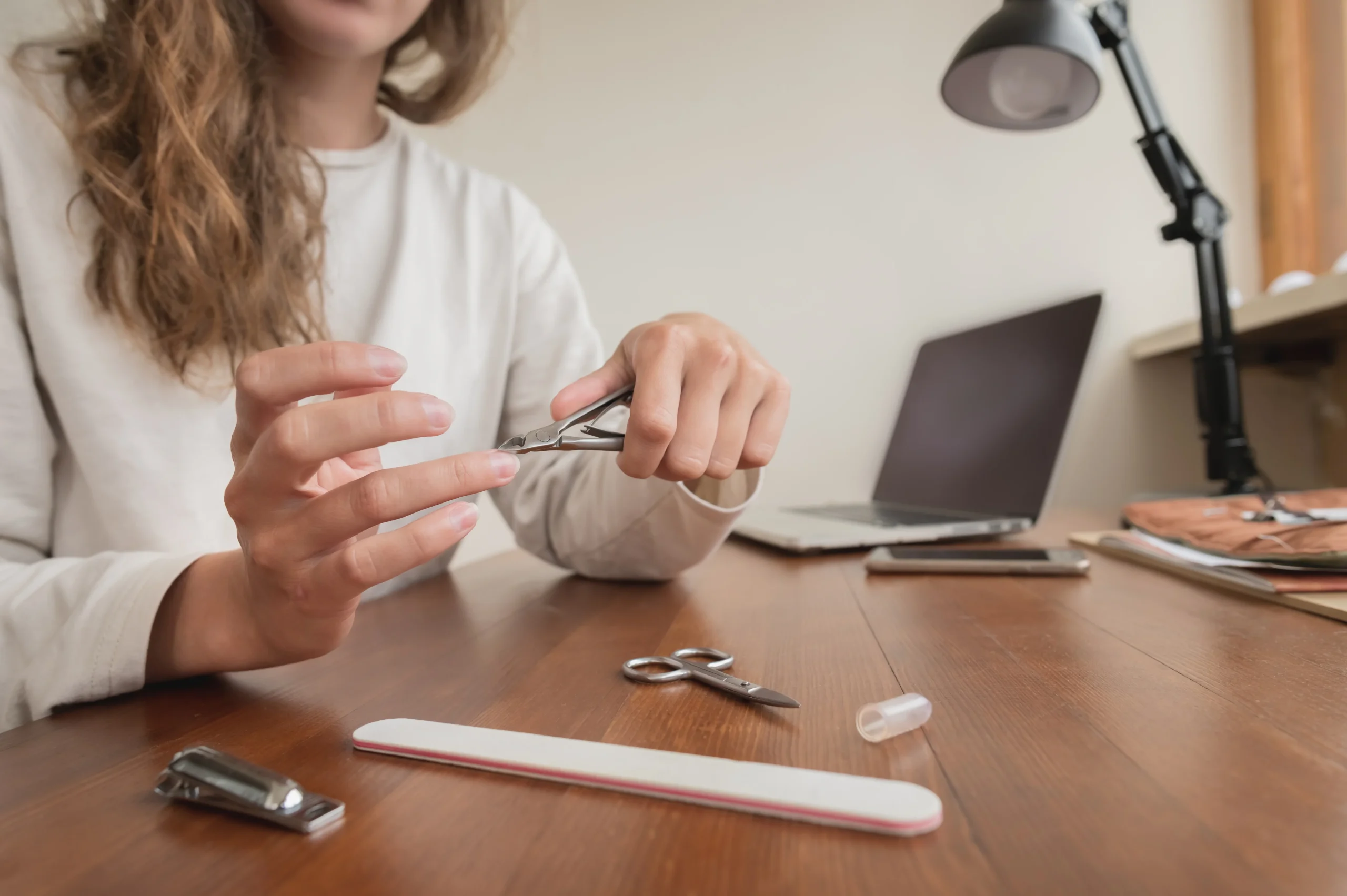 Woman moisturizing her nails as part of a daily nail care routine.