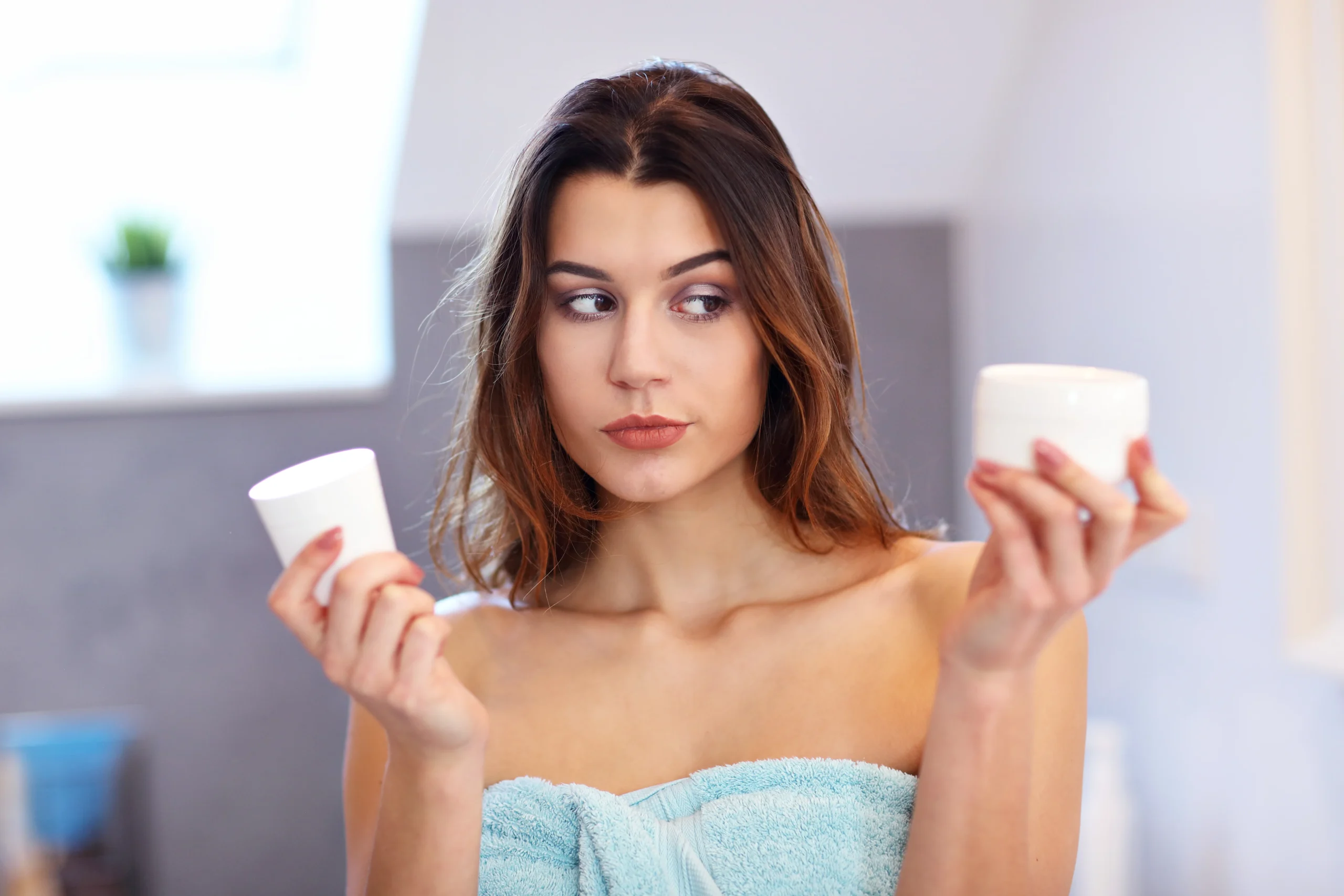 Woman applying moisturizer before foundation for all-day flawless makeup.