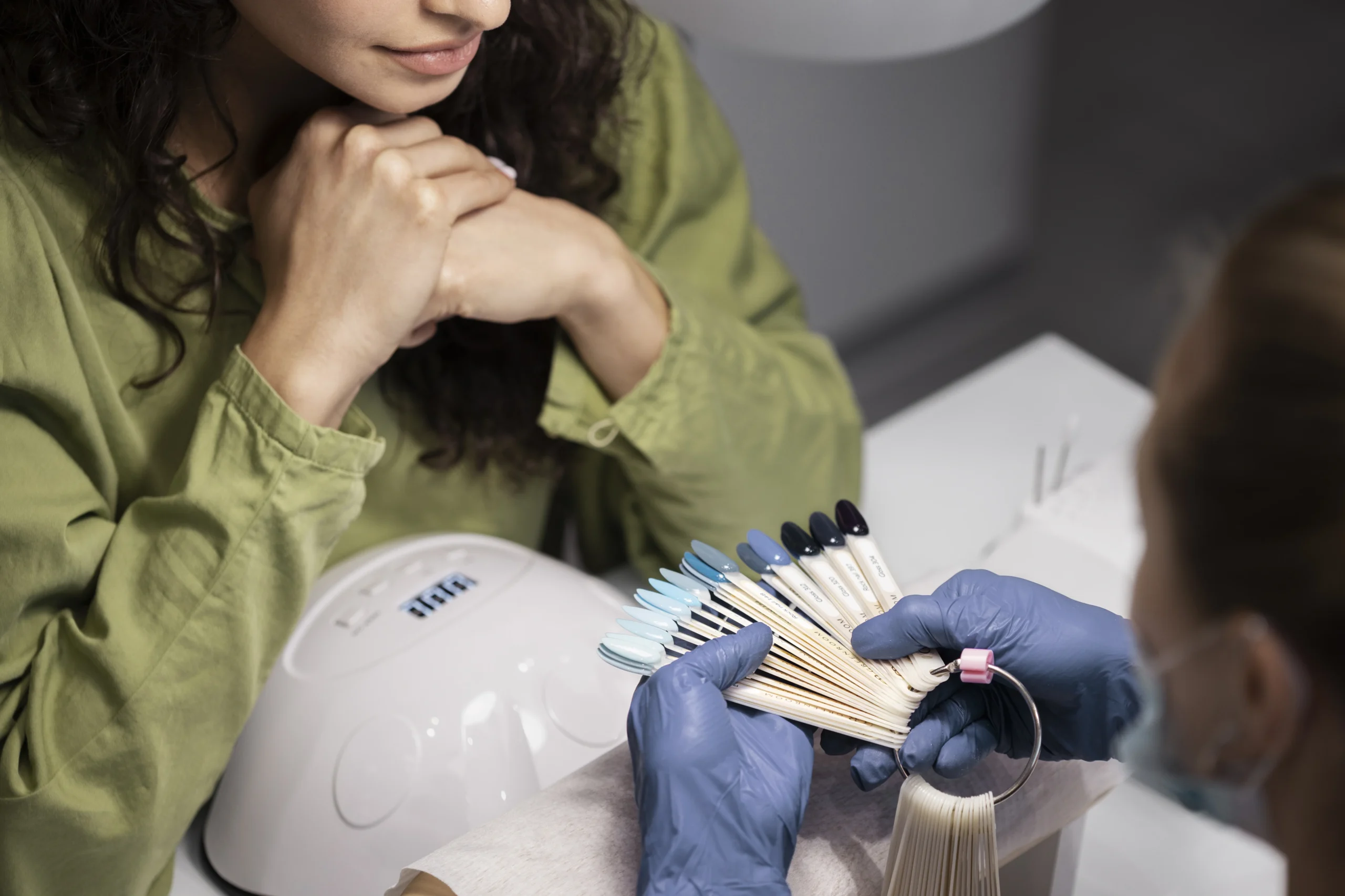 Nail technician presenting multiple nail polish shades to a client.