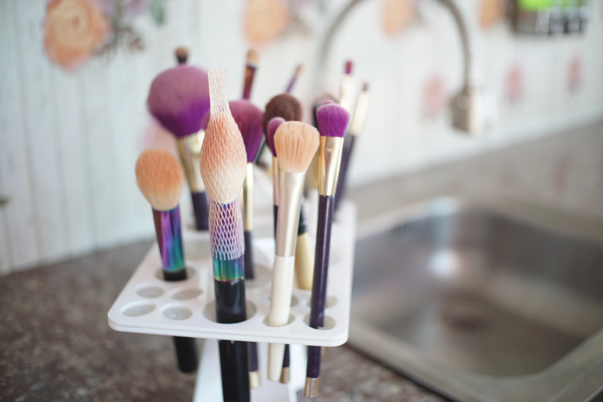 Hand cleaning a makeup brush with soap and water.