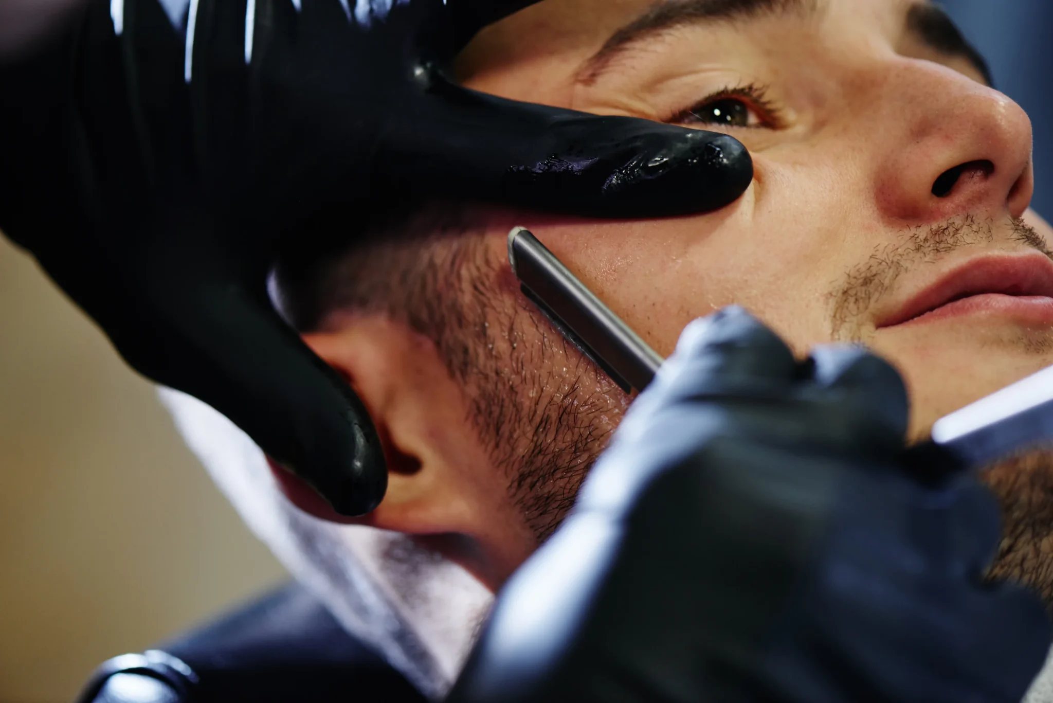 Barber shaping a man’s beard with clean, defined lines in artistic men’s grooming.