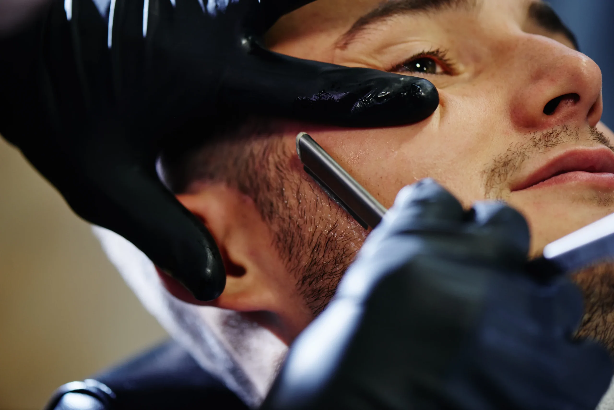 Barber shaping a man’s beard with clean, defined lines in artistic men’s grooming.