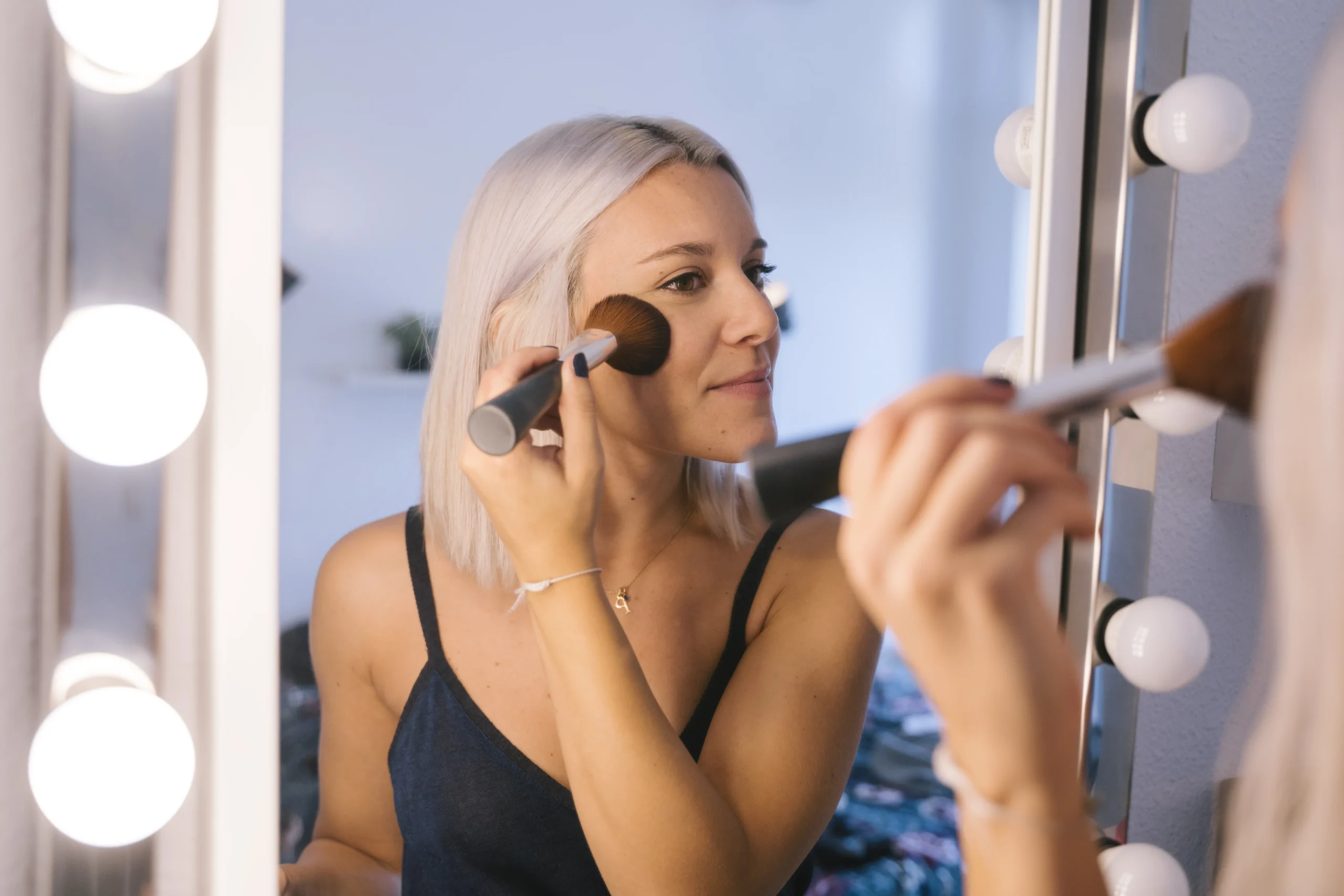 Mature woman applying hydrating primer before makeup for youthful results.