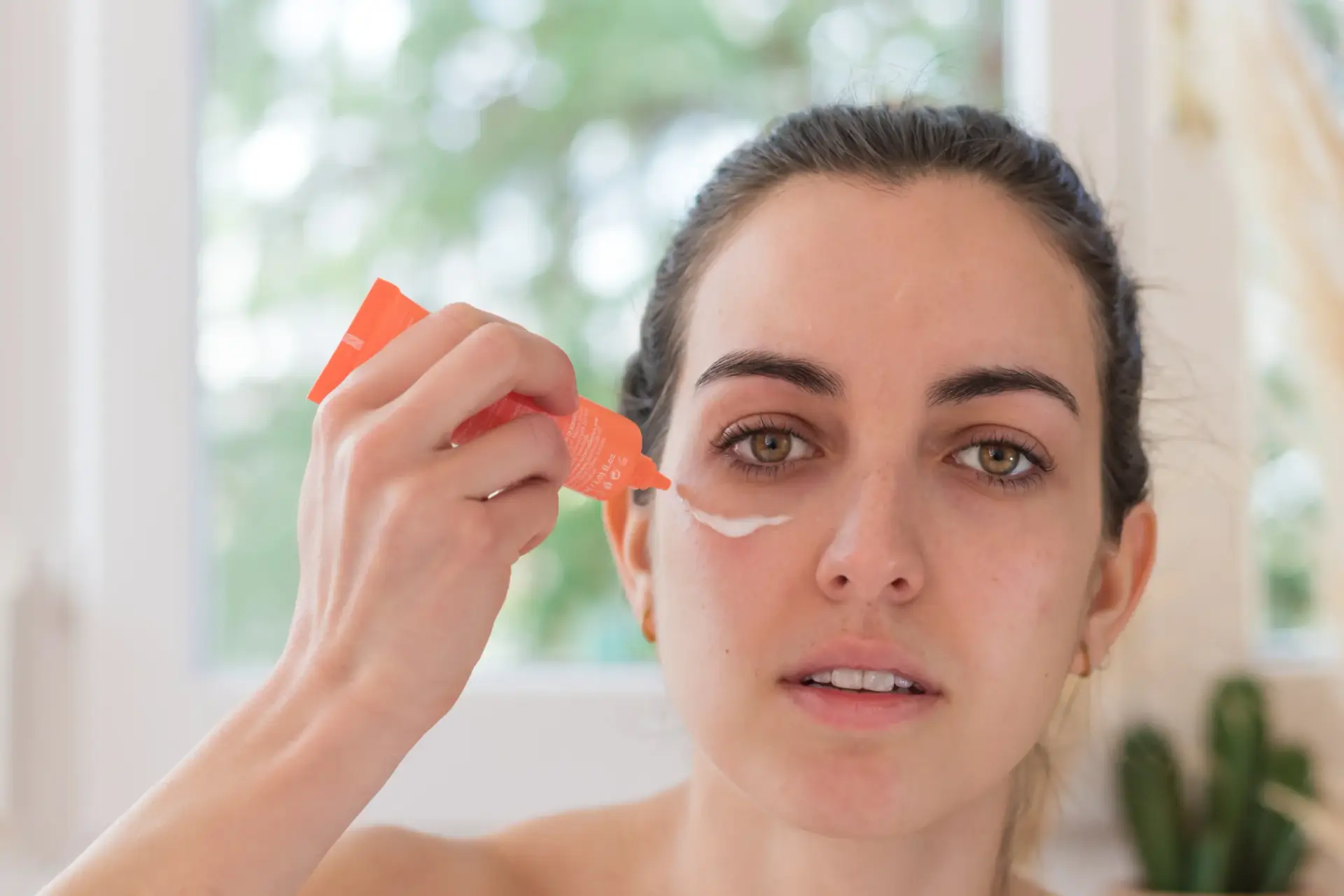 Woman applying mattifying primer to her T-zone before makeup